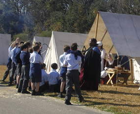 A woman dressed in 1815-era clothes talks to children