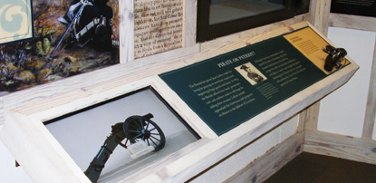A display with a computer interactive and a hands-on flintlock gun firing mechanism.