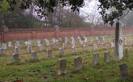 Image of national cemetery on a foggy fall day with rows of headstones and a taller monument at right