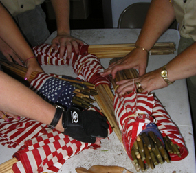 Hands of volunteers rolling up flags for storage after Memorial Day