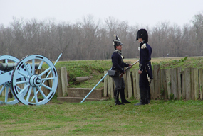 Two American soldiers in 1815 uniforms stand near a cannon at Chalmette Battlefield