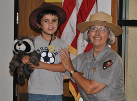 A park ranger and a little boy in a Junior Ranger hat  