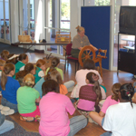 A park ranger shows a scout group how a spinning wheel works at the Acadian Cultural Center.
