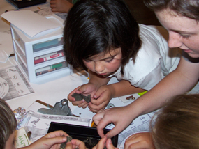 Girls bend over a science project at summer camp