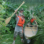 A ranger and two summer campers prepare to launch their canoe