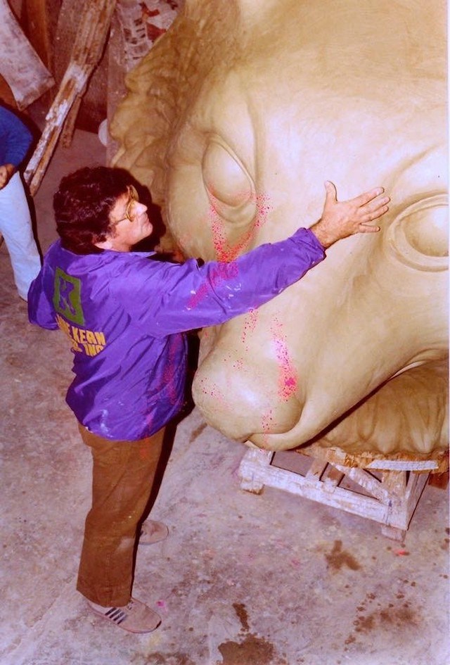 a man in purple jacket brushing a float sculpture with his hand