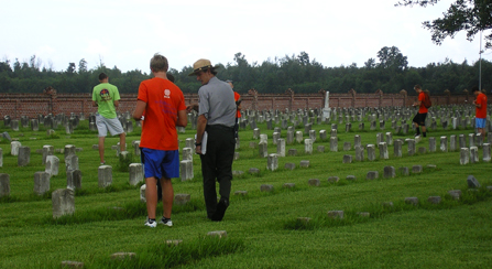 Image of park ranger talking with volunteer as they walk among headstones