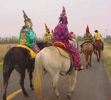 adults in colorful rompers with decorative cone shaped hats, ride horses