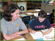 A ranger encourages a student writing an essay