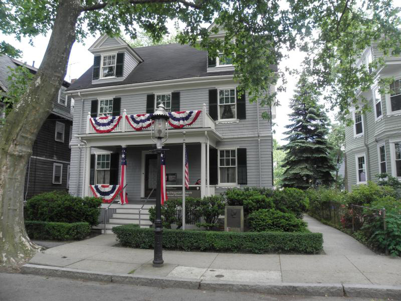 A grey, two story house is decorated with red, white and blue bunting.