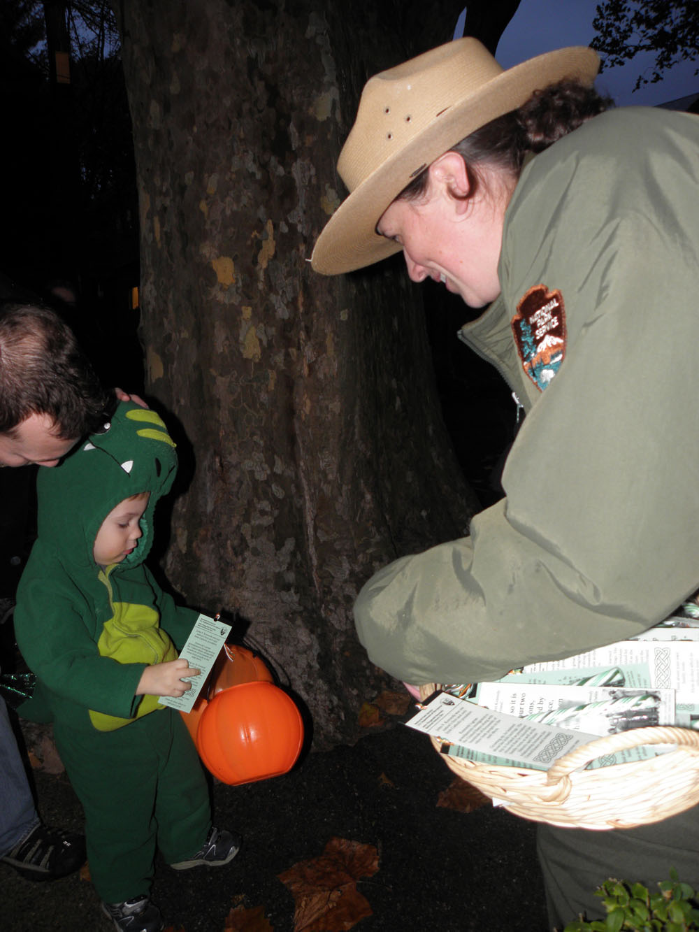 A ranger hands a child dressed as an alligator a Halloween treat.