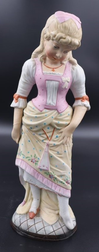 A figurine of a woman with blonde hair wearing a pink and yellow dress