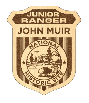 Photograph of a wooden Junior Ranger badge. "Junior Ranger John Muir National Historic Site".