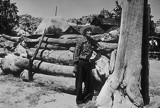 Bill Keys standing next to Joshua tree log fence
