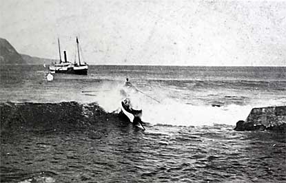 Row boat carrying new patients and cargo from large boat to Kalawao shore.