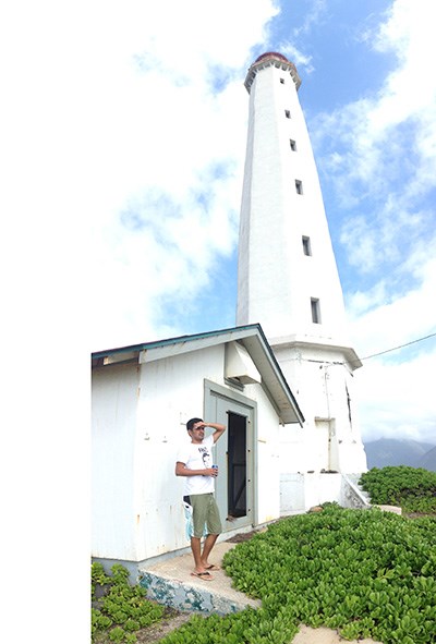 A person stands at the base of a tall, white lighthouse