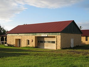 A tan building with a red-brown roof and a large garage.