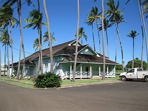 A large mint-colored building with palm trees surrounding it.