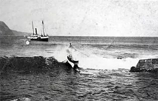 A black and white image of two boats on the ocean, one is in the waves.