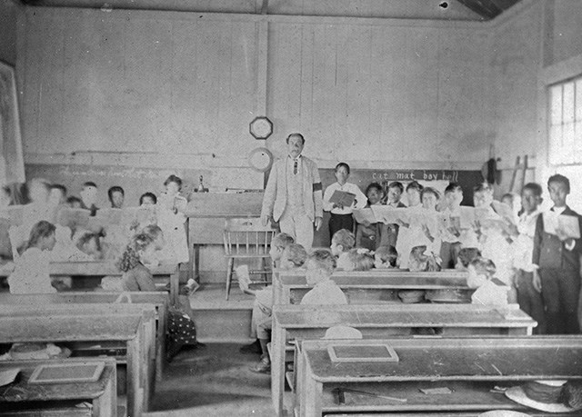 A man in a schoolhouse surrounded by children