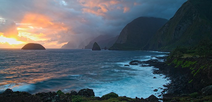 Sunrise at Kalawao with a view of two islands, the Pacific Ocean, and tall sea cliffs.