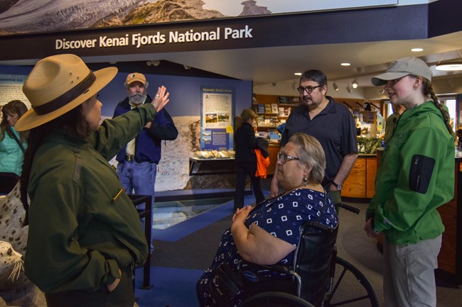 A Park Ranger speaks to an audience of four in the Kenai Fjords National Park Visitor Center