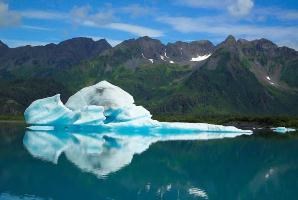A large iceberg floats in a glacial lagoon with mountains in the background.