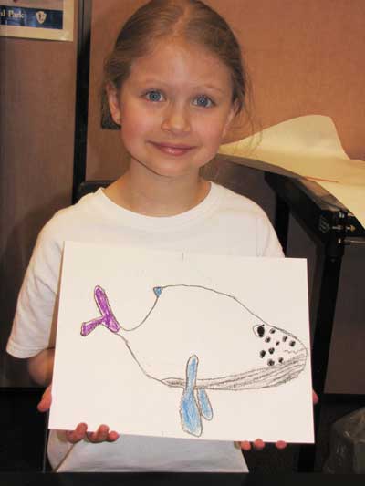 Student holds up marine mammal themed art for National Park Week Art Show