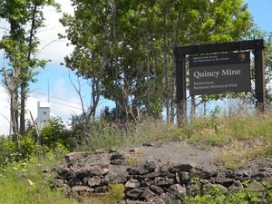 The Quincy Unit park sign is in the right foreground, with the top of the No. 2 shaft-rock house in the left background.