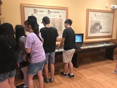A group of students examine exhibits in a museum.