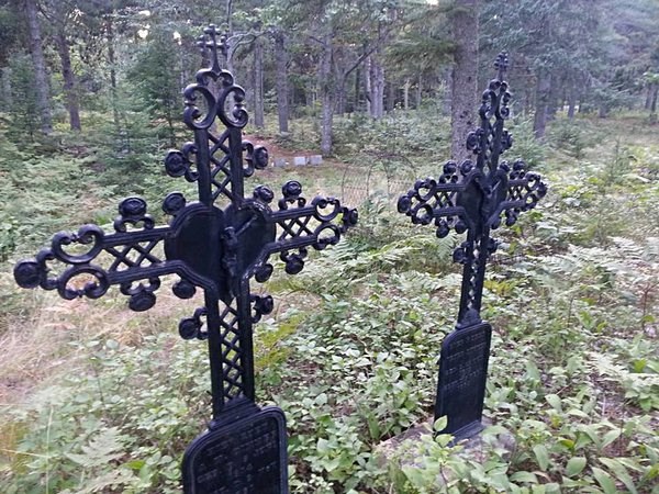 Two cross grave markers are surrounded by a small fence.