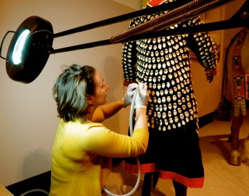 Conservation intern Nicole Peters treating an elk-tooth Crow Dress at the Eiteljorg Museum of American Indians & Western Art in Indianapolis, IN