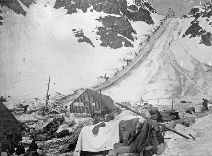 Historic Photos of the Chilkoot Trail with a line of hiker going over the summit