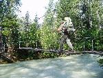 hiker on suspension bridge over gray-blue water