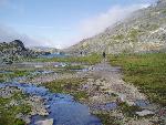 Hiker, level trail, blue skies, many rocks on path