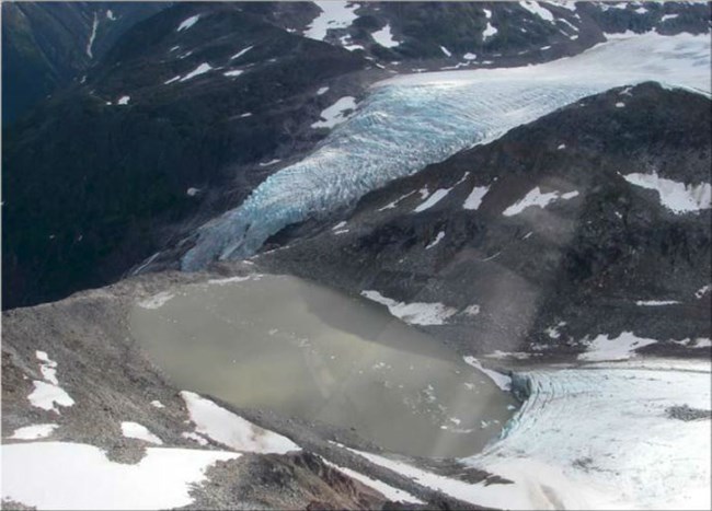 Aerial view of a mountain lake with glacial ice nearby.