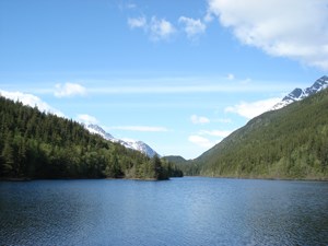 View across calm lake surrounded by trees and mountains