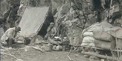 Klondiker's camp with lean-to and supplies at the foot of canyon, Chilkoot Trail, Alaska, 1897
