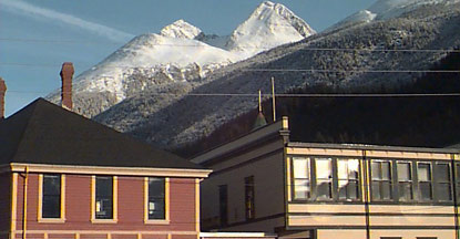 Historic gold rush buildings in front of snow-capped mountains