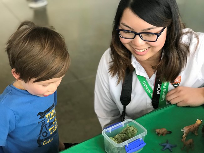 A volunteer and a child examine moss on a table