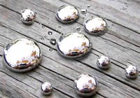 Nine reflective silver bubbles sit on a piece of wood.