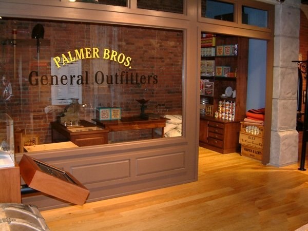 a display with a false storefront labeled Palmer Brothers General outfitters.  Inside are prop barrels, boxes, and cash register