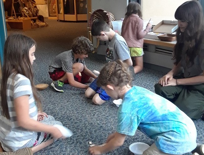 Several kids play with games on the floor in the visitor center.