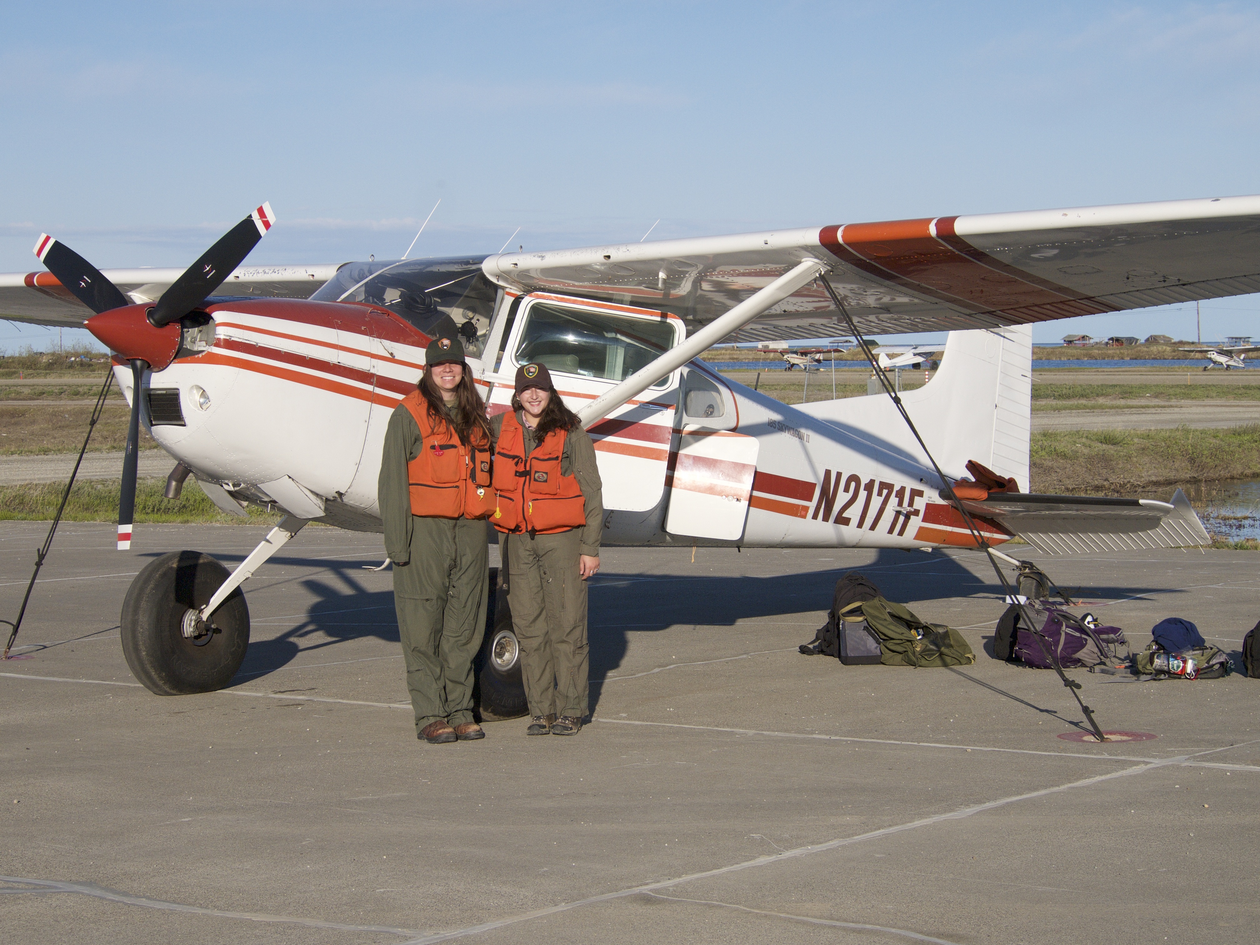 Two park service staff pose next to a small plane.