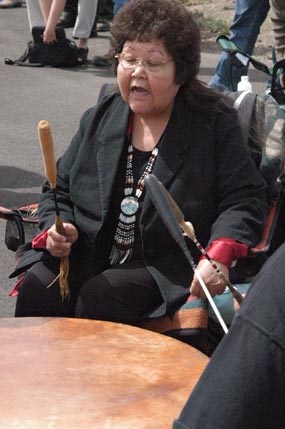 A woman beats a drum whole singing