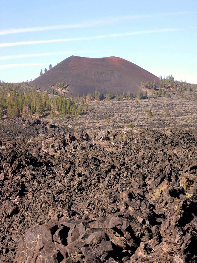 A bare butte, with a rocky field of basalt in the foreground