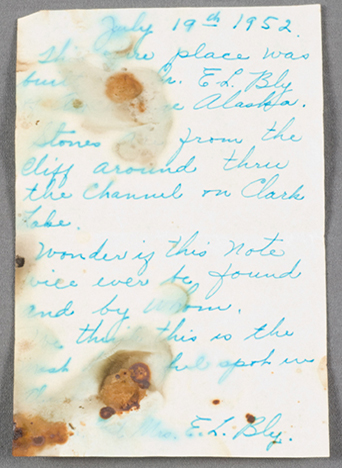 handwritten note in blue ink on unlined paper. The note is blotched with what appears to be water stains.