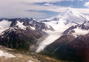 aerial view of a snow-covered volcano surrounded by rocky and snowy mountains