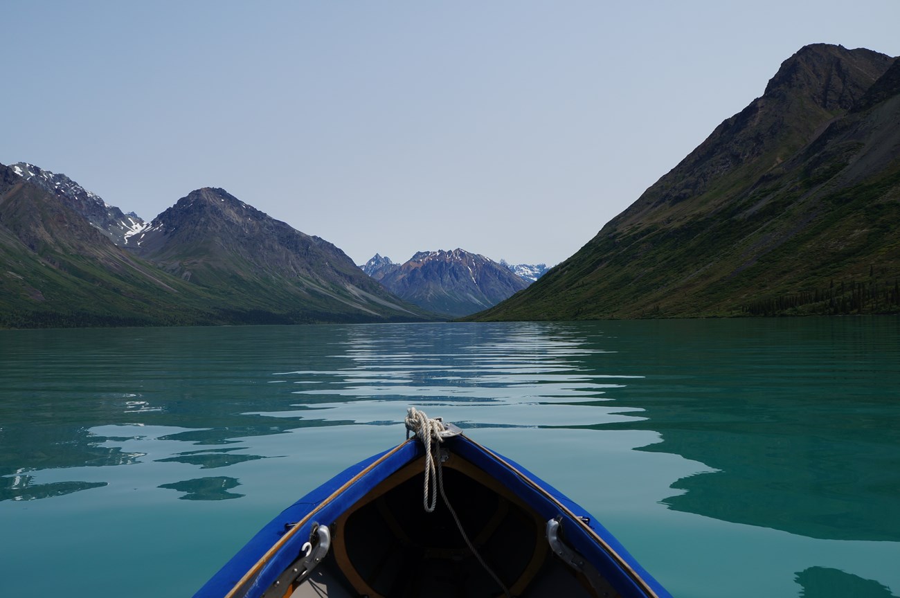 view from a blue canoe of mountains and a turquoise lake