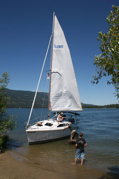 Sailboat loading visitors for a short tour of the lake. White sailboat with sail up.